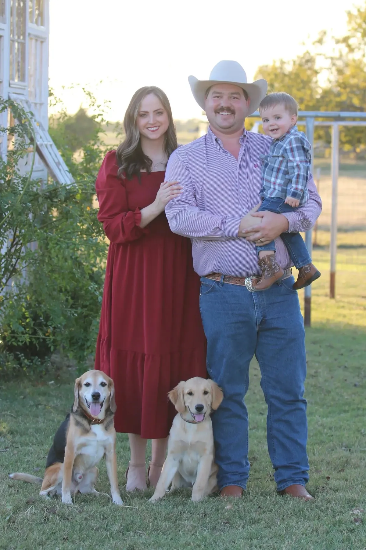 Matt and Haven Zajic with their young son and two dogs on the lawn at the farm